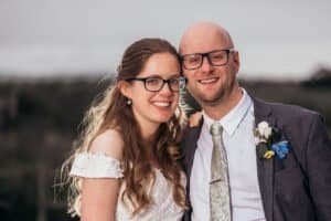 Smiling Newlyweds in wedding attire with glasses outdoors