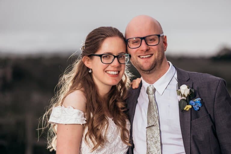 Smiling Newlyweds in wedding attire with glasses outdoors