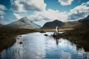 Bride and groom stand on a outcrop in scenic mountain landscape in the Isle of Skye