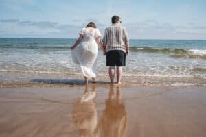Couple holding hands walking on tranquil beach shoreline pre-wedding shoot Seaburn