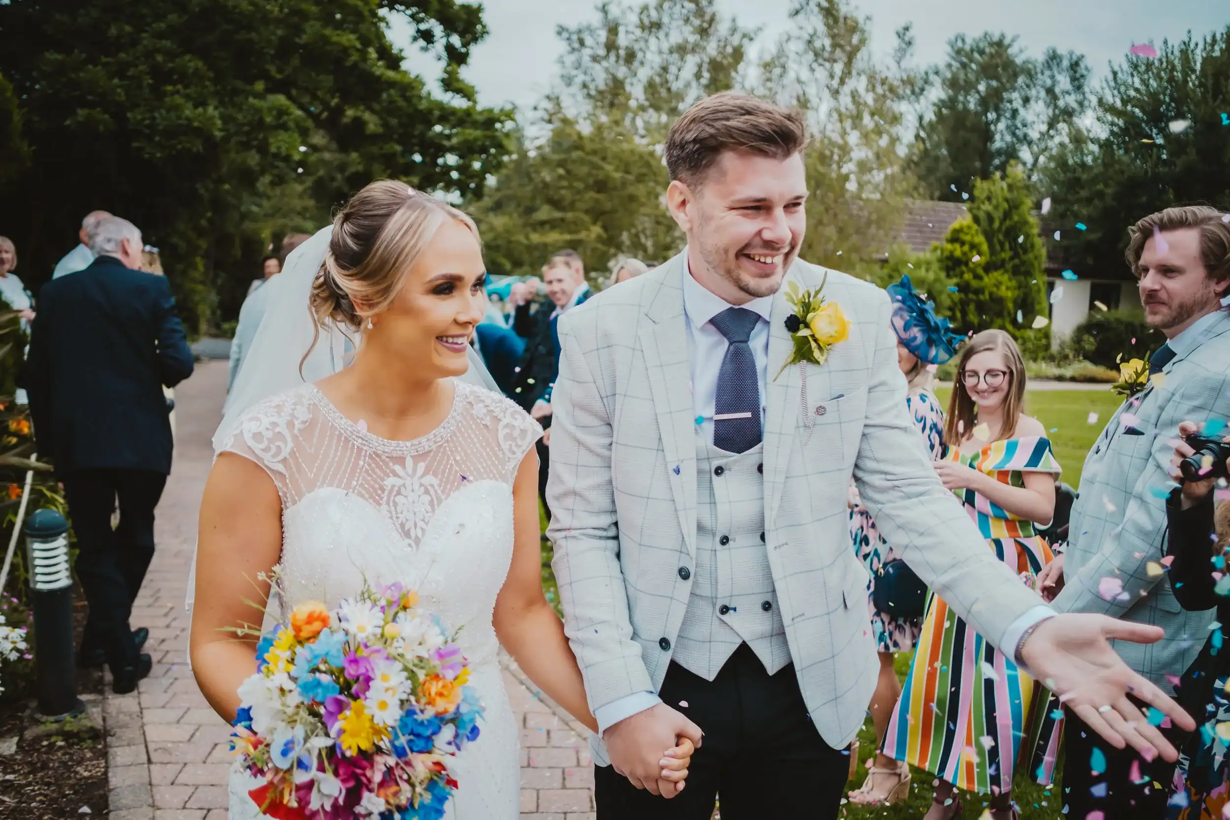 Smiling couple walks after wedding ceremony with guests