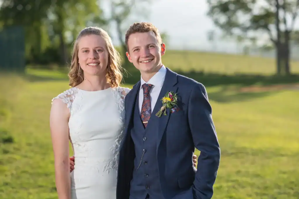 Newlyweds smiling in wedding attire outdoors at golden hour in Rothbury, Northumberland