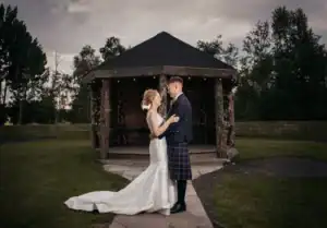 Bride and groom share a romantic moment by a rustic gazebo at Silverwood Resort in Perth, Scotland