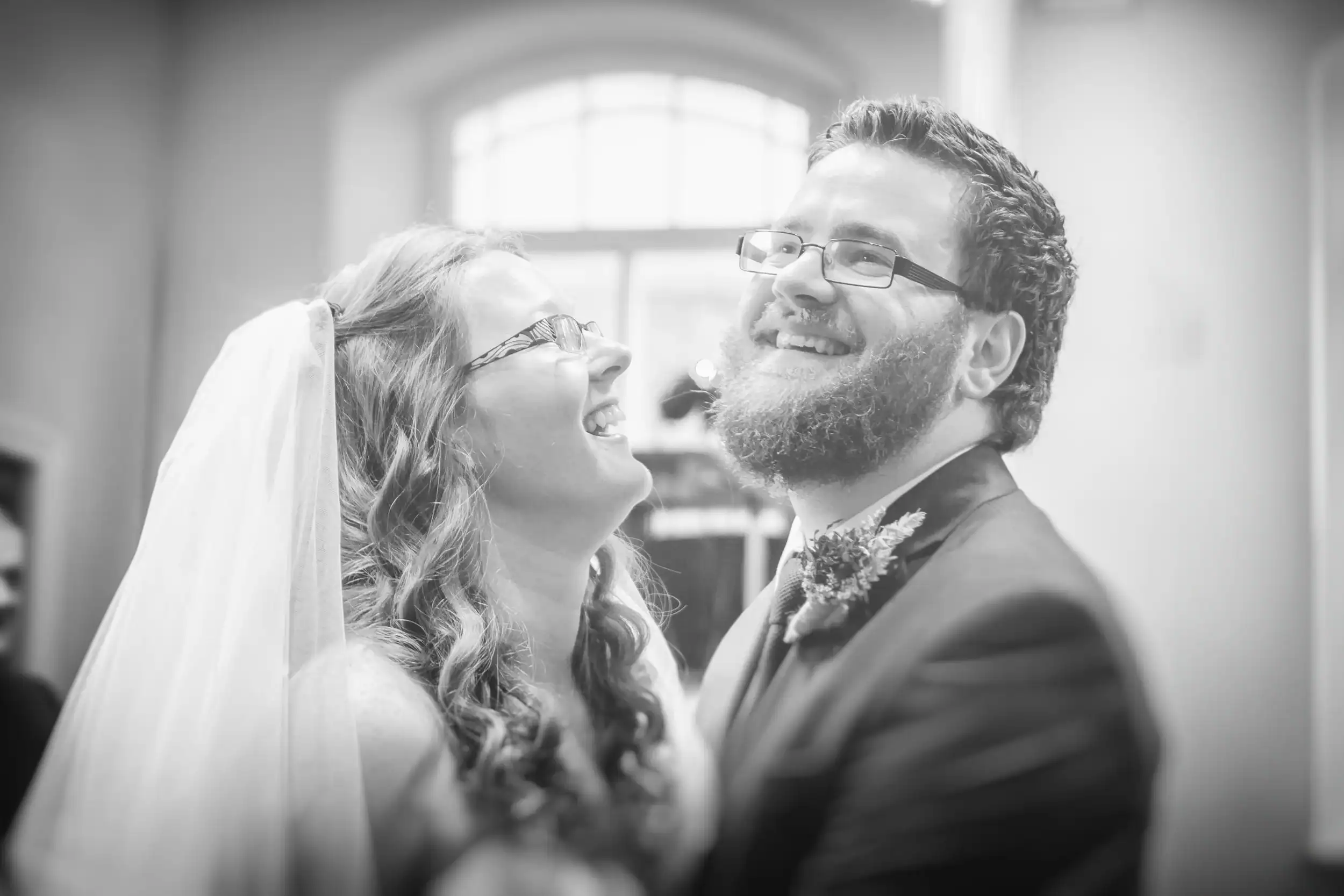 Bride and groom laughing together, black and white