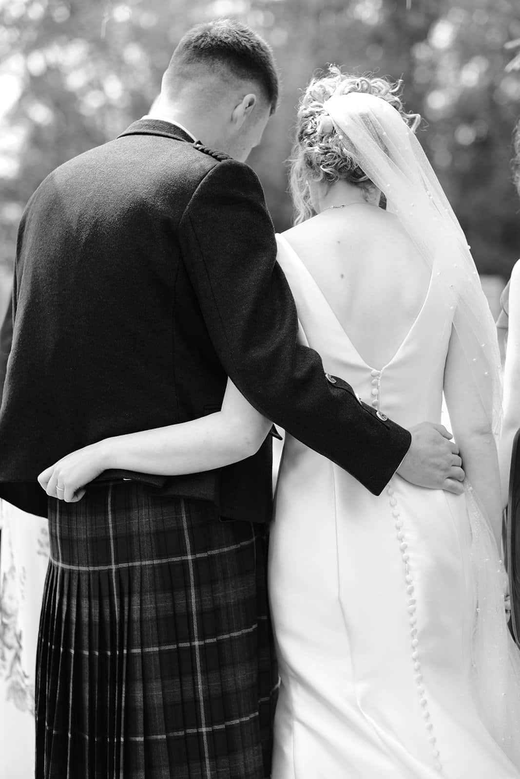 Bride and groom embrace in traditional wedding attire