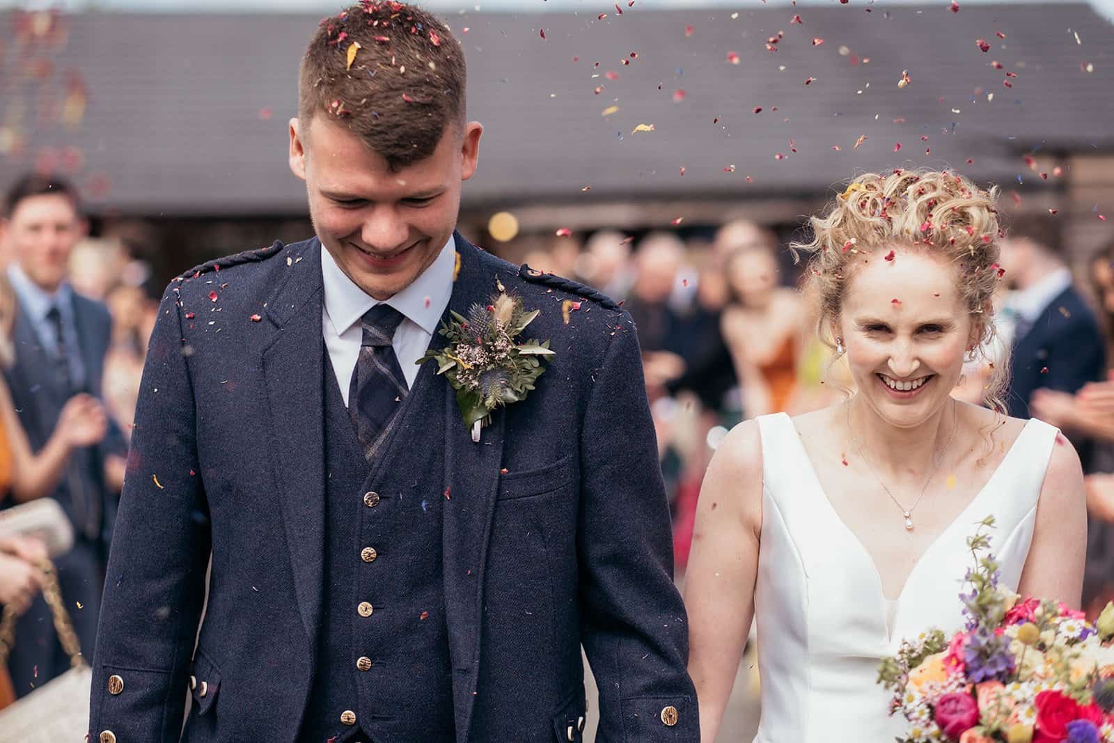 Bride and groom smiling amid wedding celebration confetti