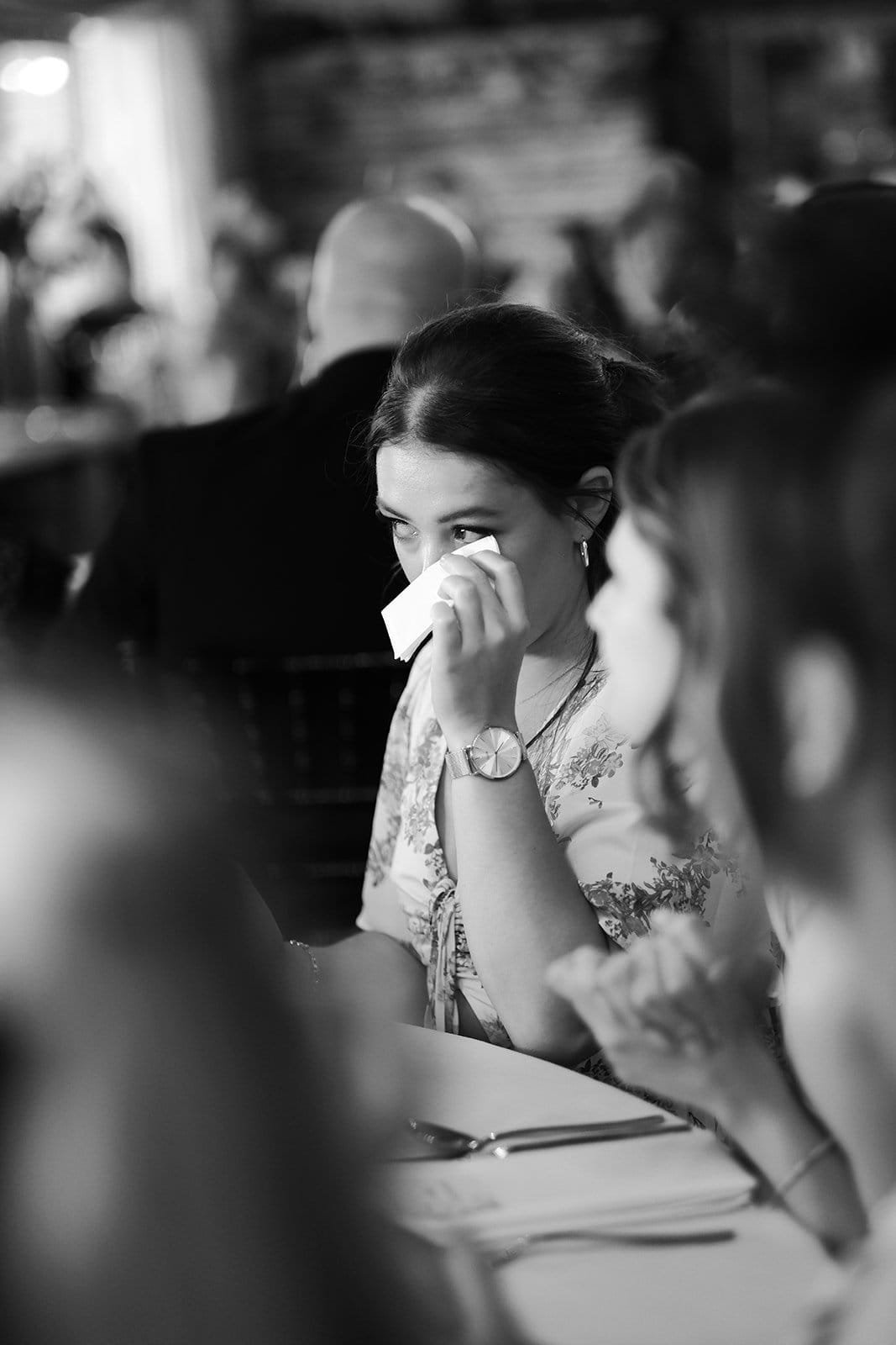 Woman wiping tears at a formal event in monochrome setting