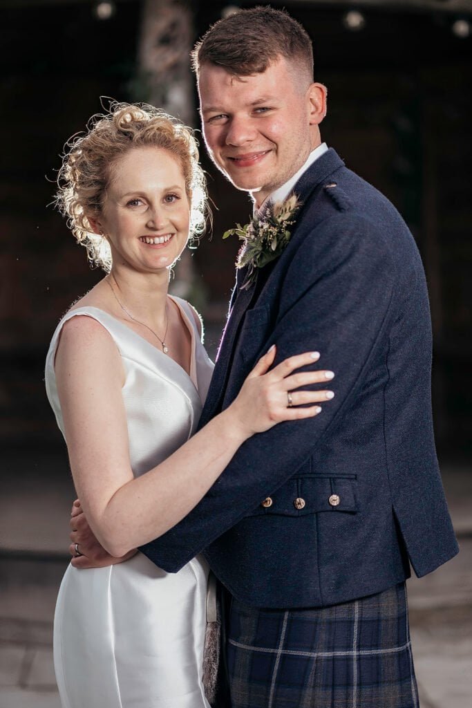Couple in wedding attire smiling and embracing warmly