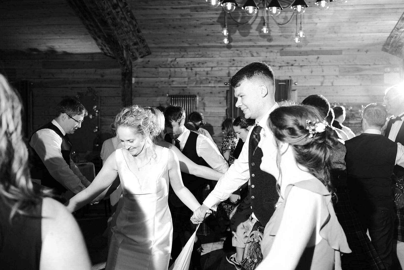 People joyfully dancing in a rustic wedding reception venue