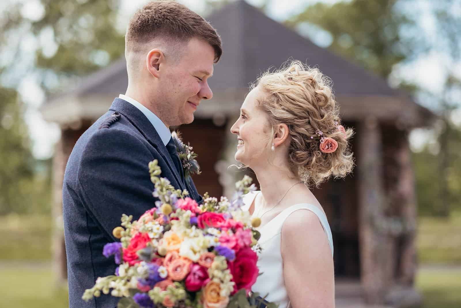 Bride and groom smiling with coloruful bouquet outdoors at Silverwood Resort in Perth