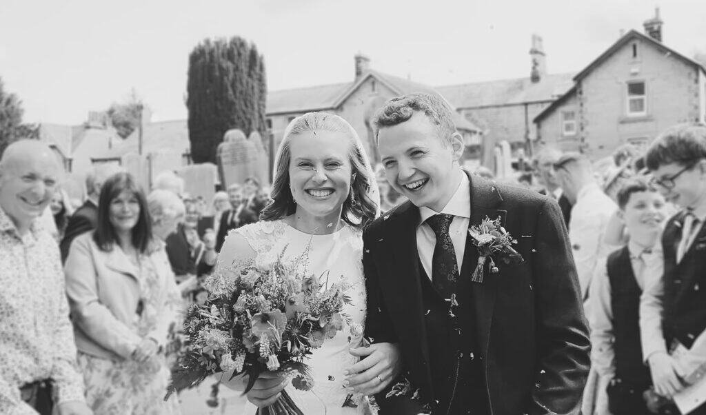 Newlywed couple celebrating with guests and confetti
