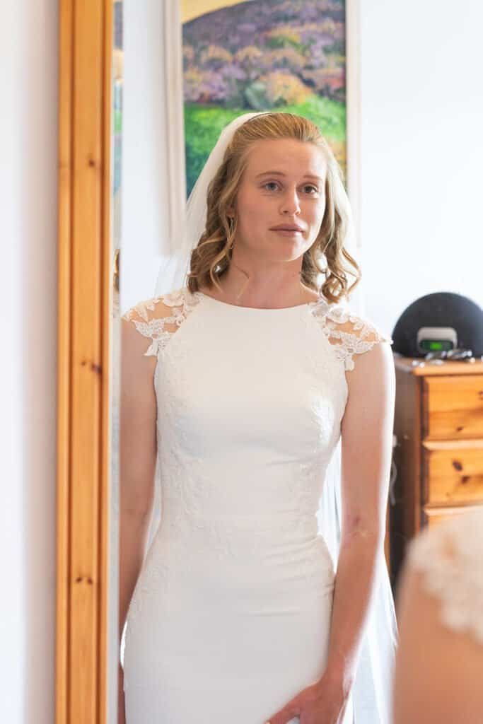 Bride in elegant wedding dress looking in a mirror reflection