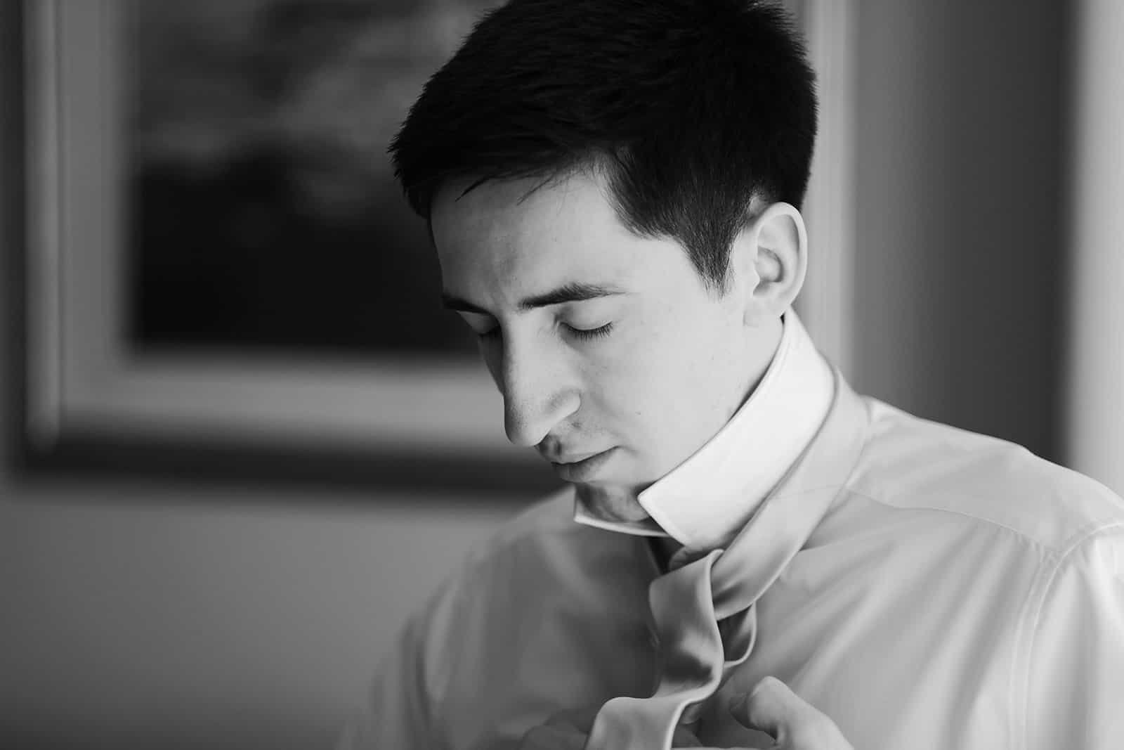 Man adjusting shirt collar in black and white portrait image
