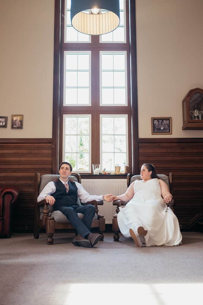 Couple sitting in elegant room holding hands by large window
