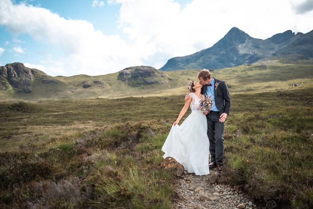 Bride and groom share a romantic kiss in scenic mountains