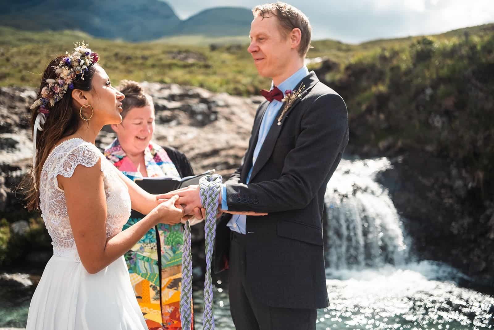 Couple celebrating outdoor wedding by a scenic waterfall.