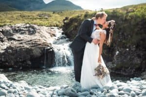 Bride and groom kissing by a mountain waterfall on the Isle of Skye