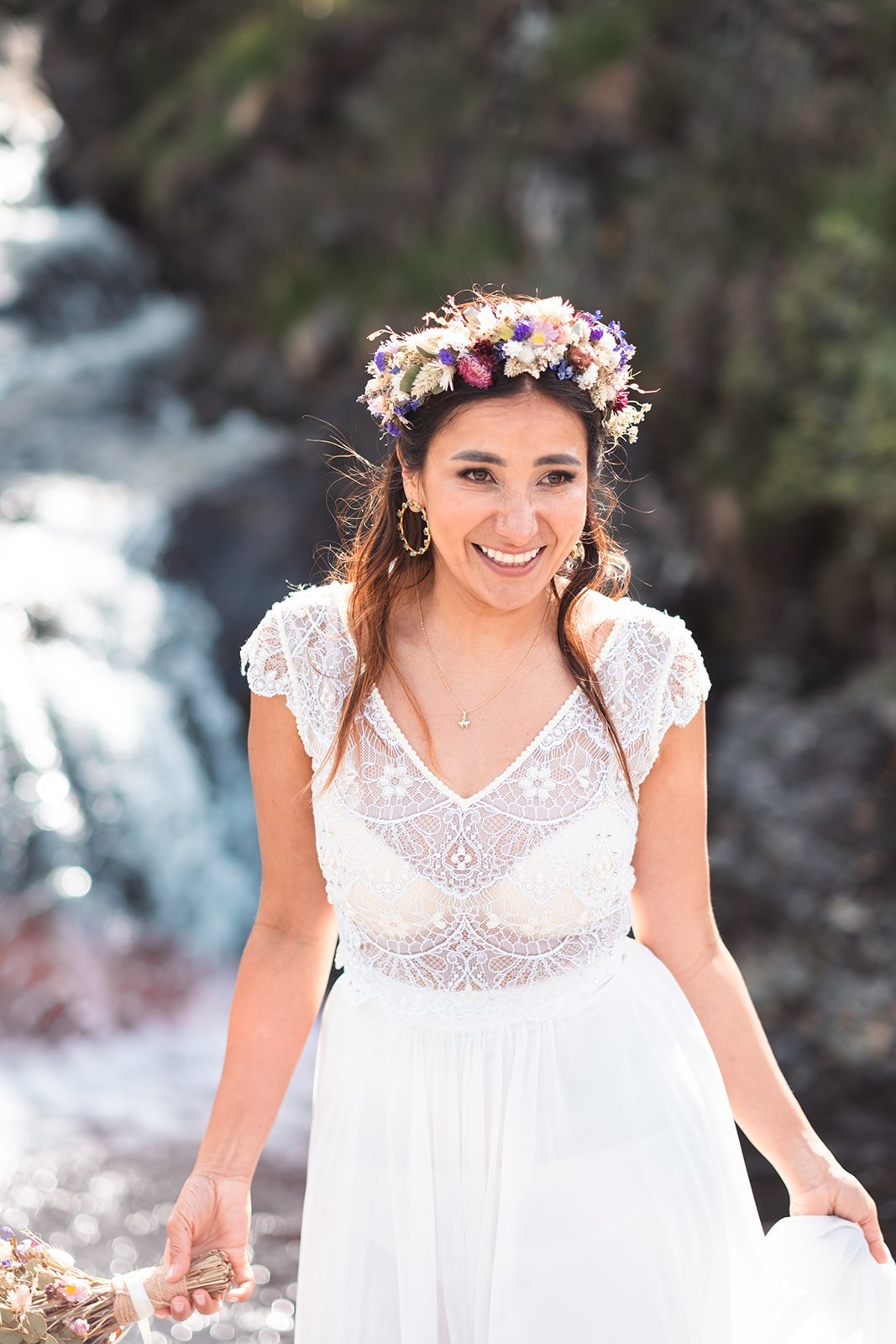 Bride with floral crown smiling near a waterfall in Isle of Skye