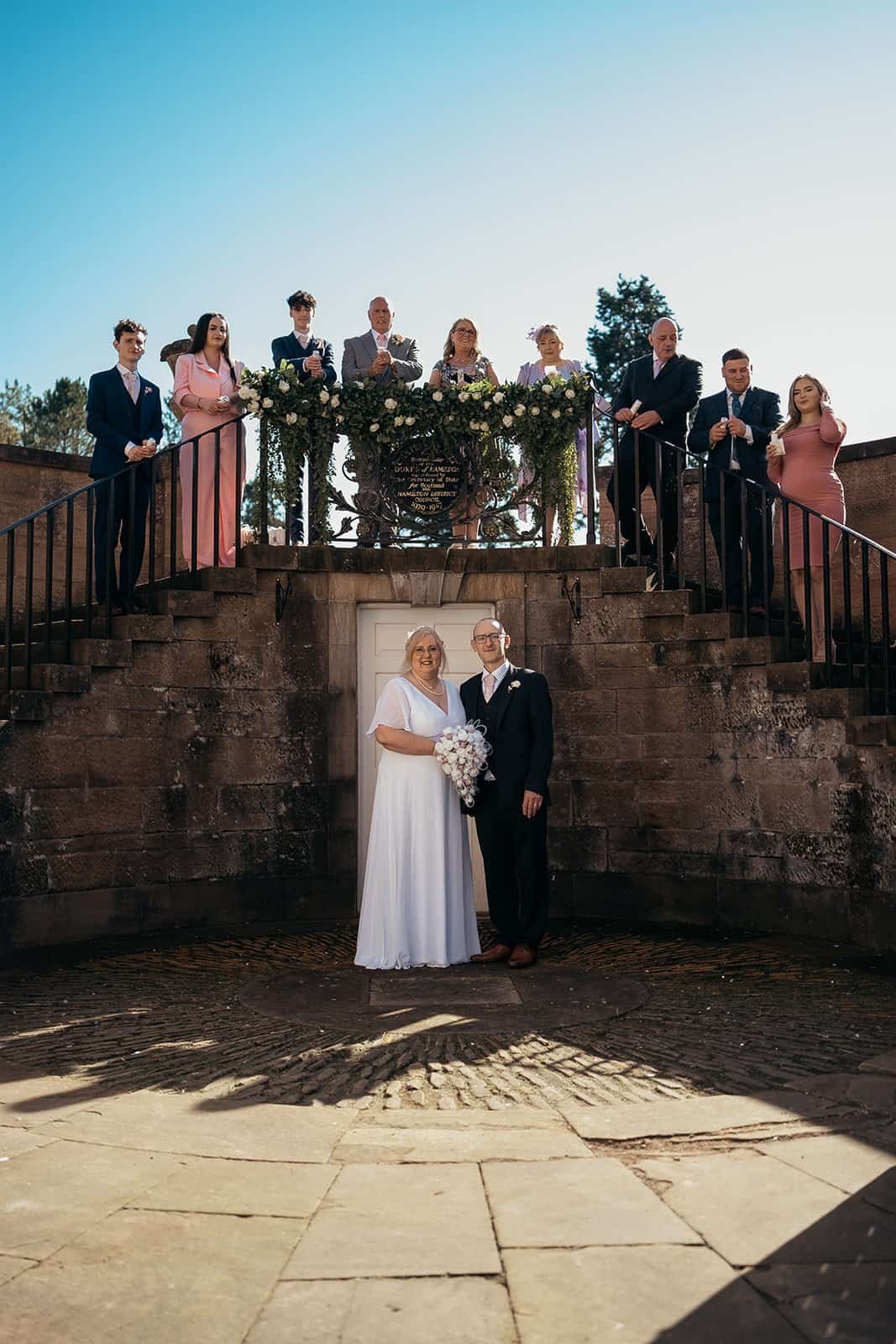 Bride and groom with wedding party on elegant stone stairs
