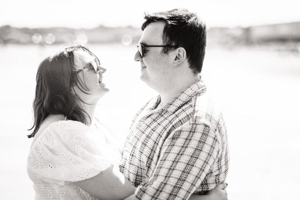 Smiling couple embracing in bright sunlight at the beach