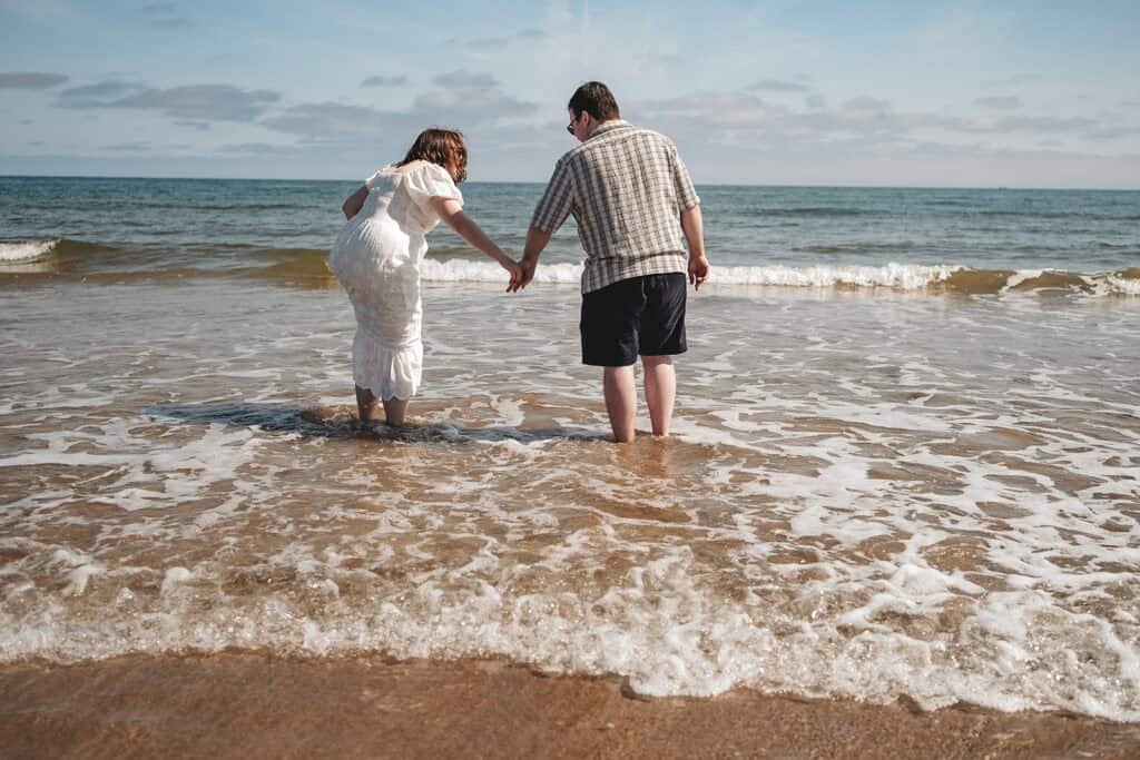 Couple holding hands while wading in the ocean waves