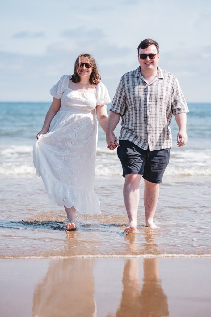 Couple holding hands walking on a sunny beach day
