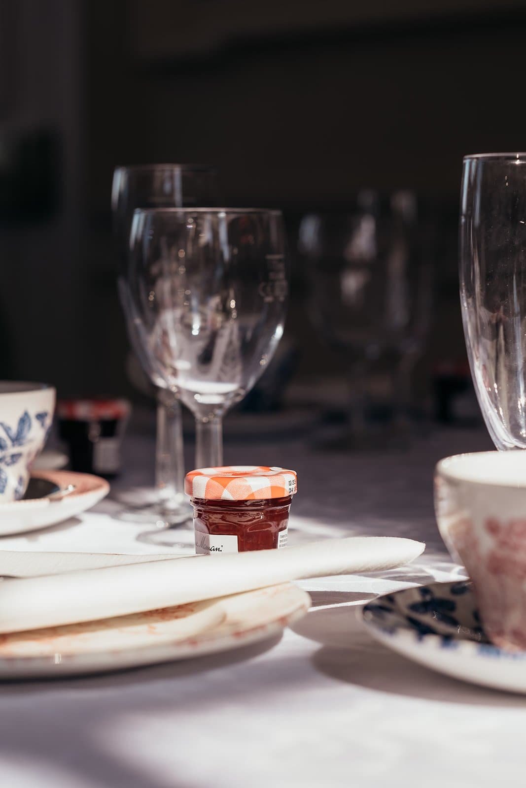 Elegant table setting with glasses and jam jar in soft light