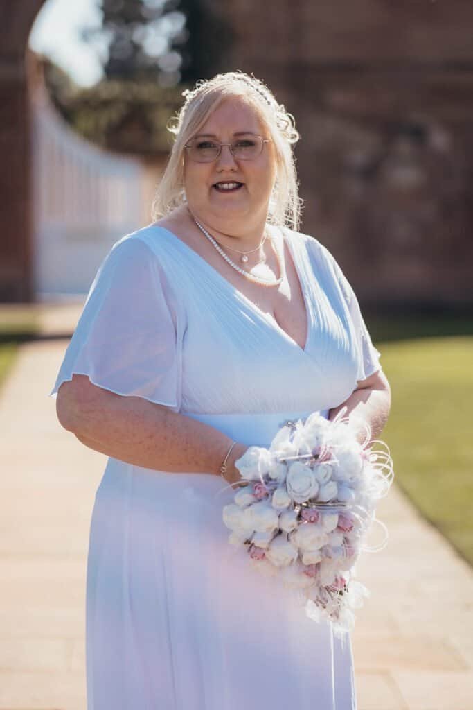 Smiling bride in a white dress holding a beautiful bouquet