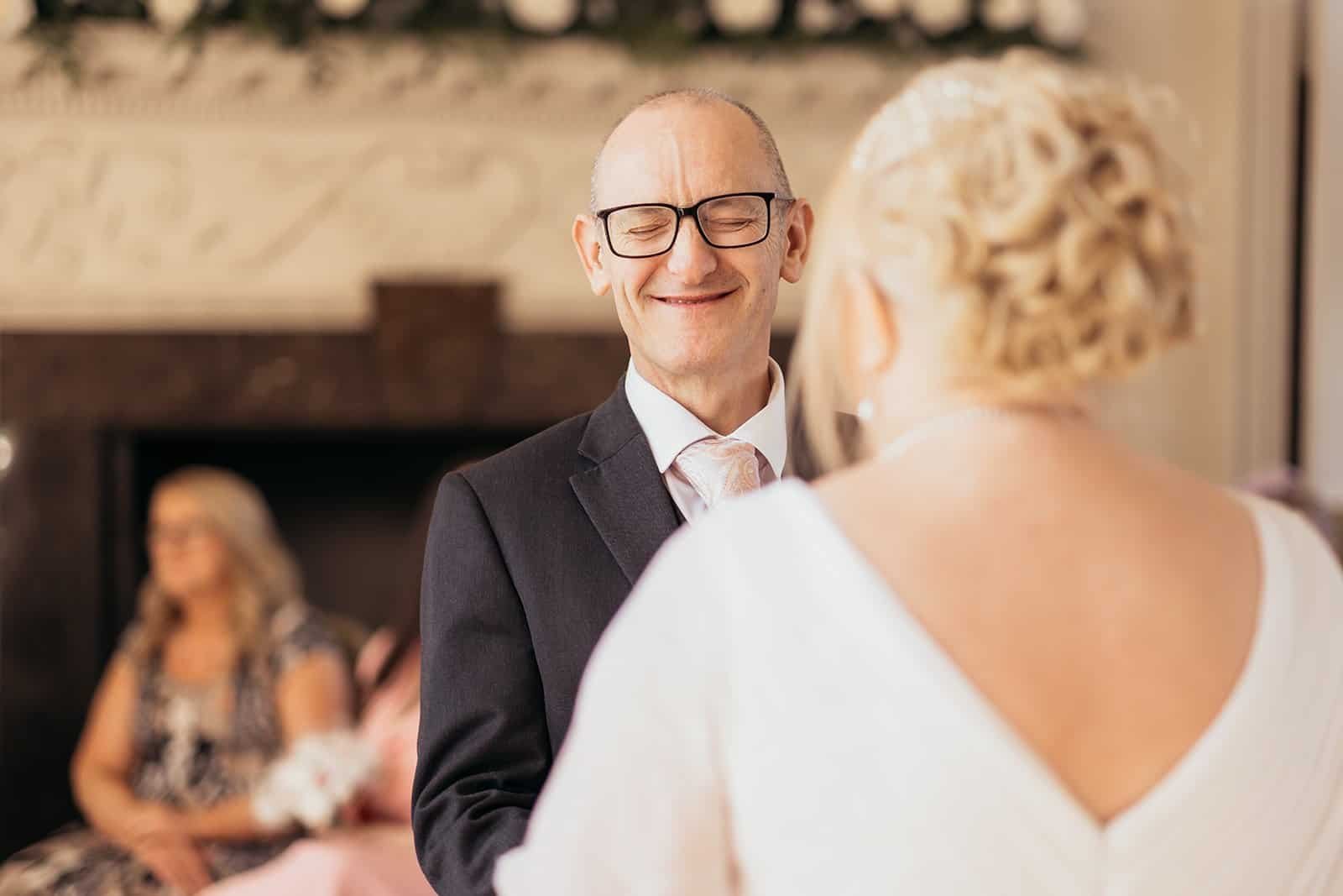Man smiling during a wedding ceremony indoors