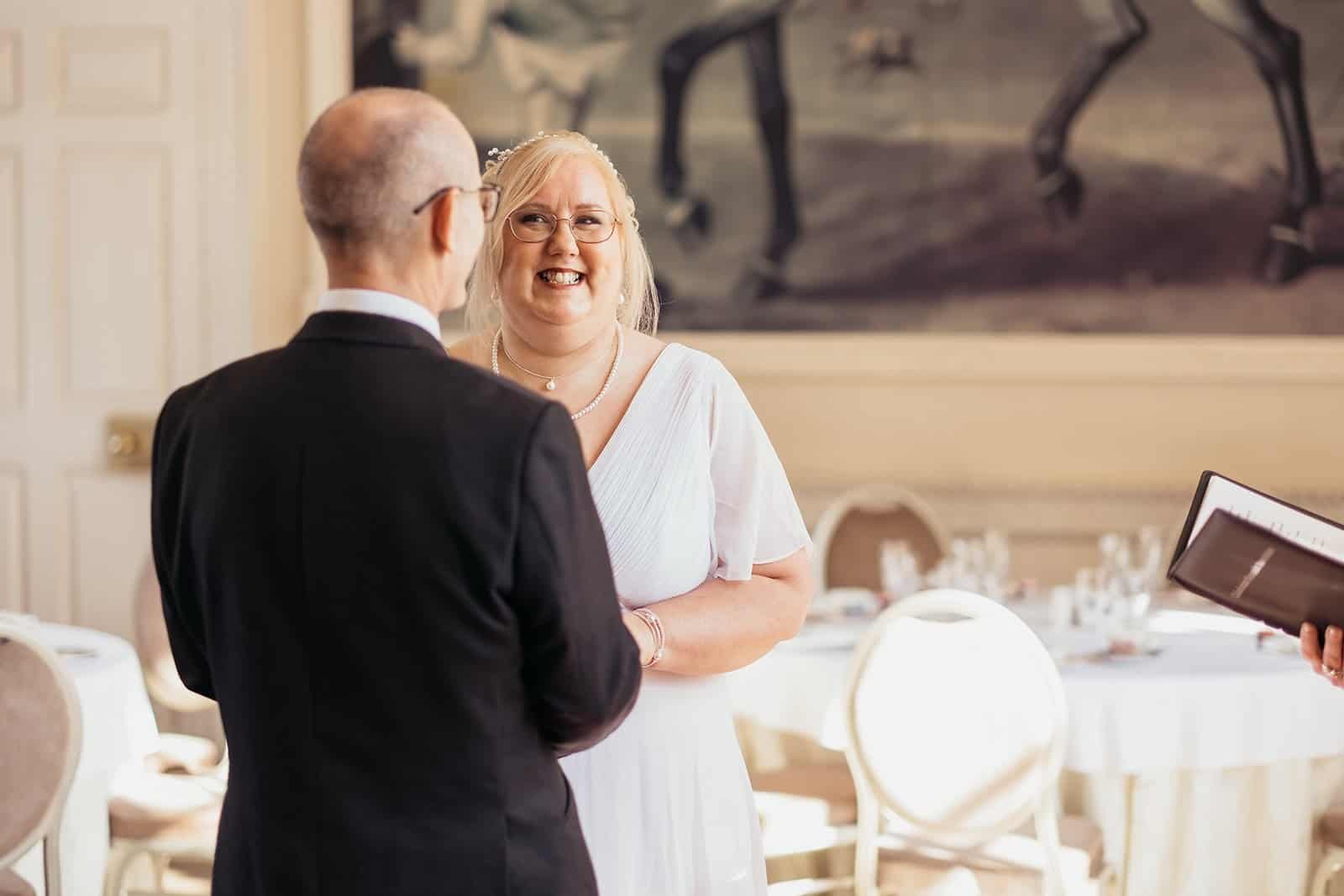 Wedding ceremony with smiling couple exchanging vows indoors