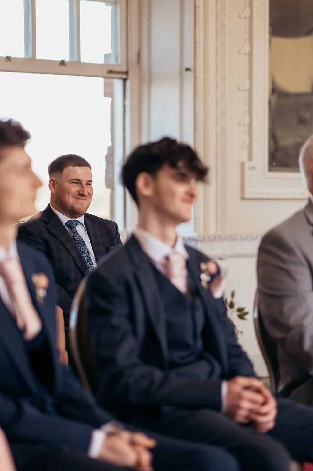 Groom smiling with groomsmen in a wedding ceremony setting