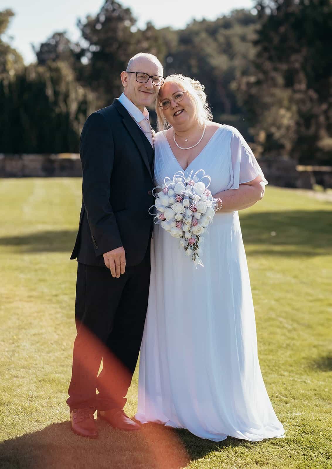 Smiling couple posing together at a wedding ceremony outdoors