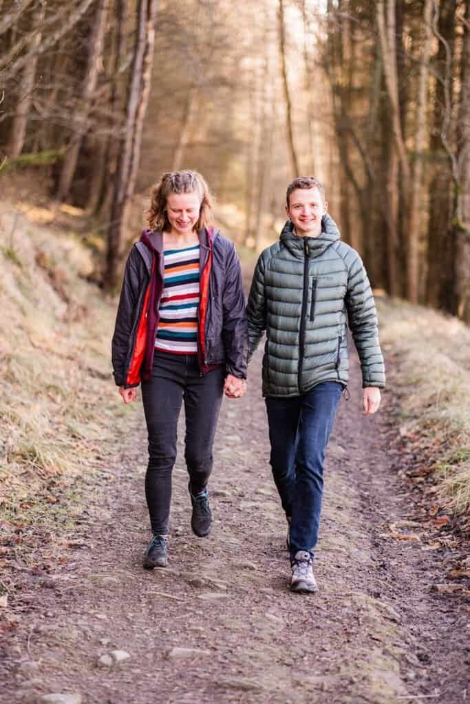 Couple walking on forest path during a cold winter morning engagement shoot
