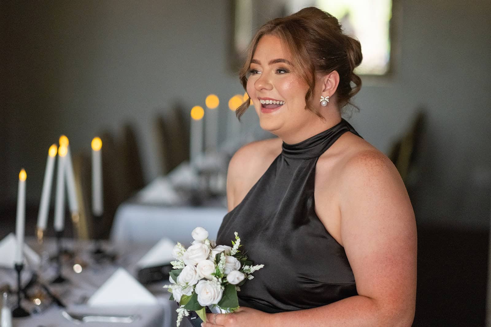 Woman smiling in elegant black dress holding white flowers