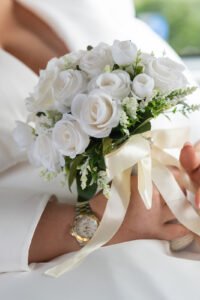 Woman holding elegant white rose bouquet at wedding ceremony
