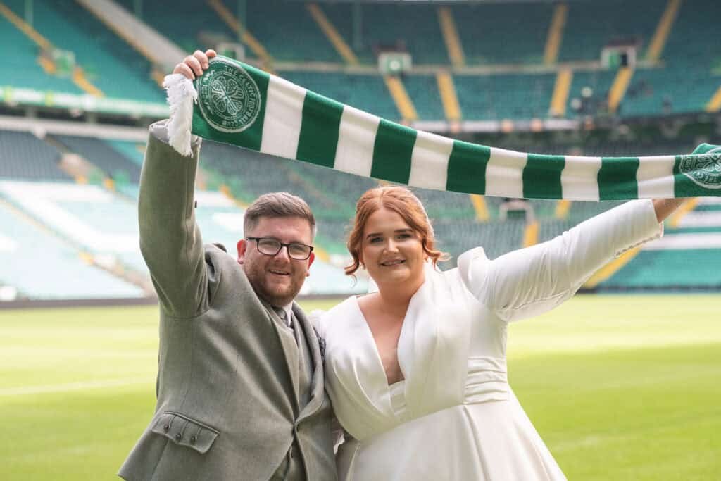 Bride and groom celebrating in a stadium with a scarf