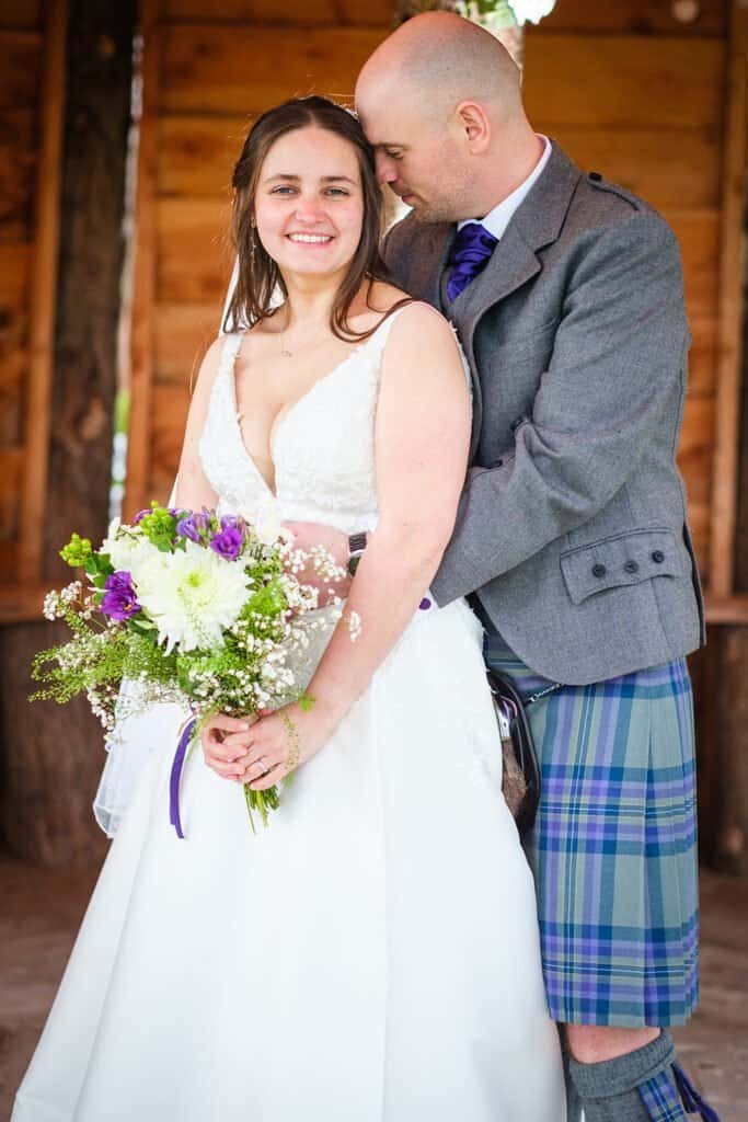 Bride and groom embrace in beautiful rustic wedding setting