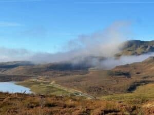 Mist lifting over the hills and a winding road beside a loch on the Isle of Skye