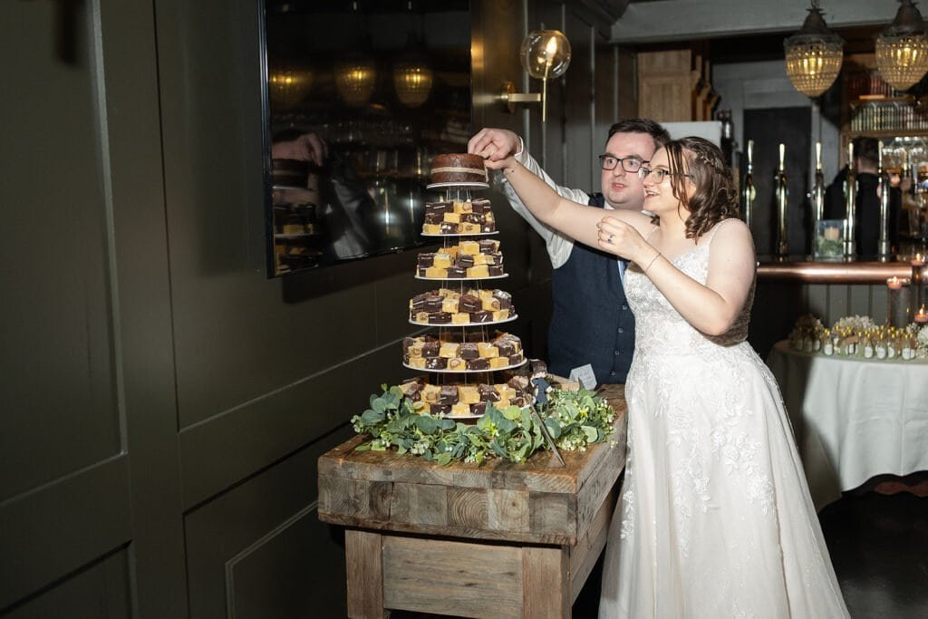 Bride and groom cutting tiered wedding cake at reception