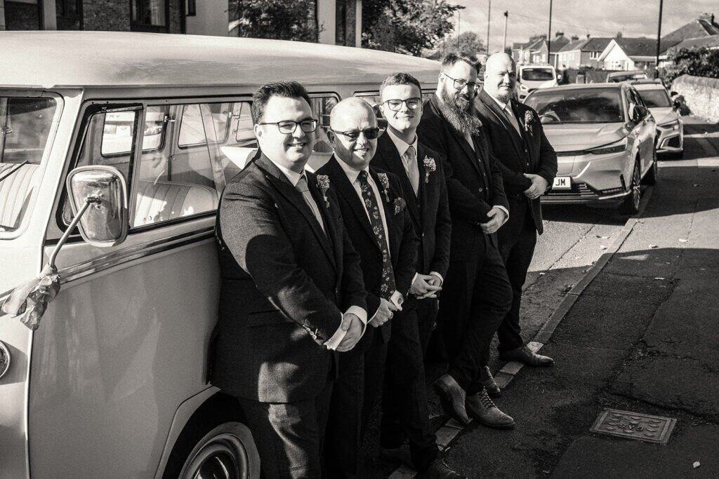 Groomsmen standing beside classic car on a sunny day