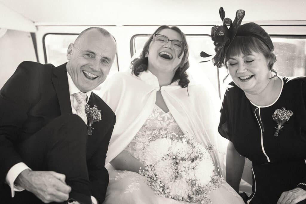 Joyful wedding celebration with three smiling attendees inside car
