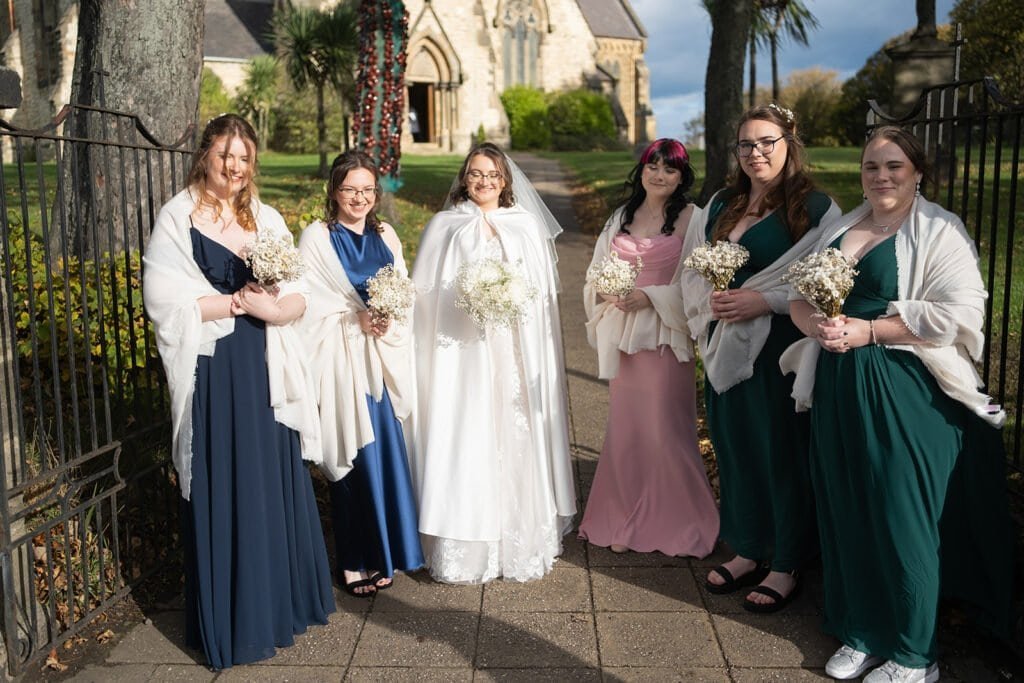 Bridal party in elegant dresses outside church on sunny day
