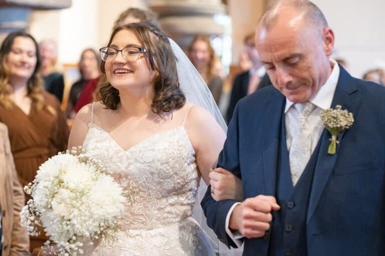 Bride walking down the aisle with her father at a wedding reception