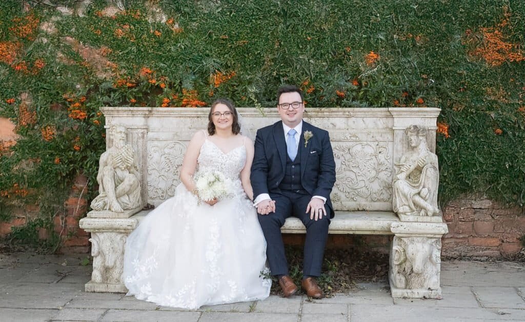 Bride and groom sitting on a stone bench outdoors