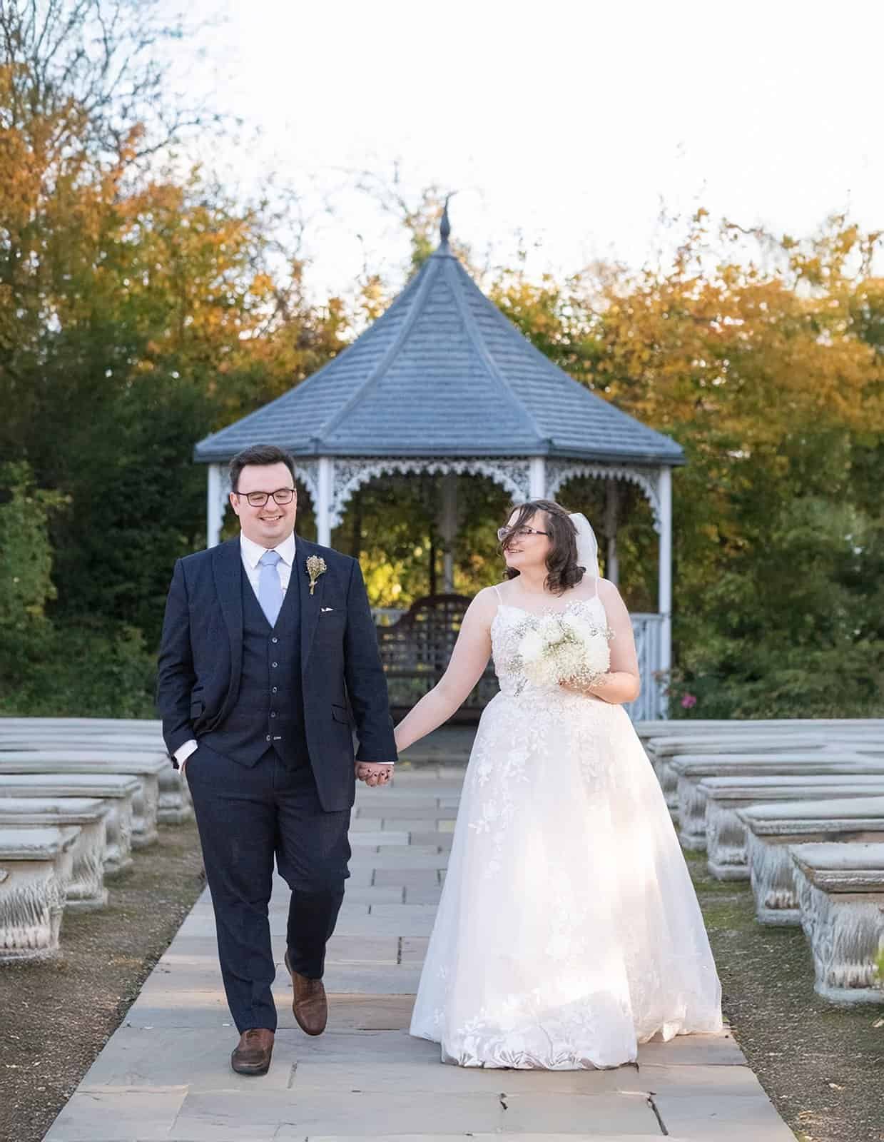 Bride and groom walking hand in hand in garden setting at Bowburn Hotel
