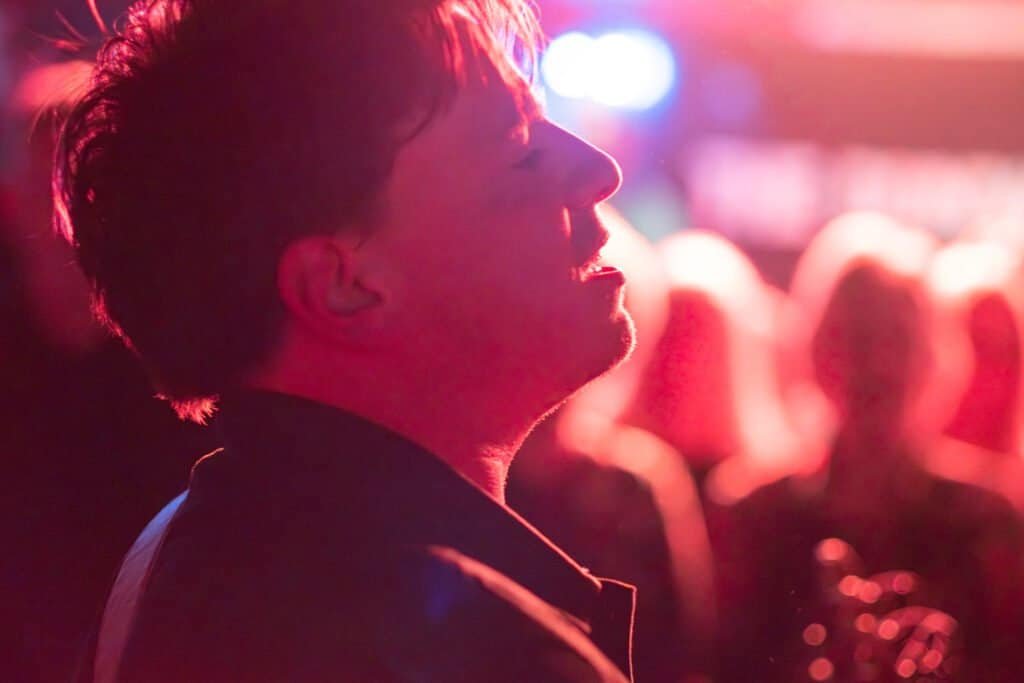 Musician immersed in live performance under vibrant stage lights