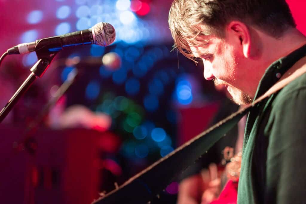 Guitarist performing on stage with colorful lights background