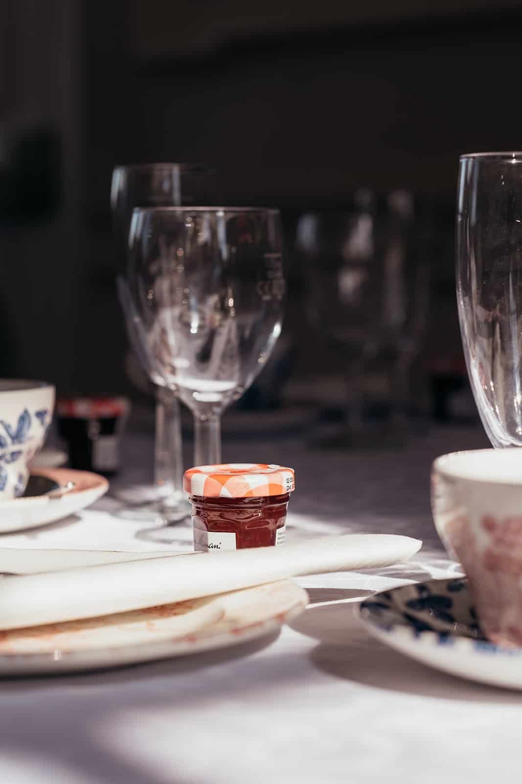 Elegant table setting with glassware and jam jar in sunlight