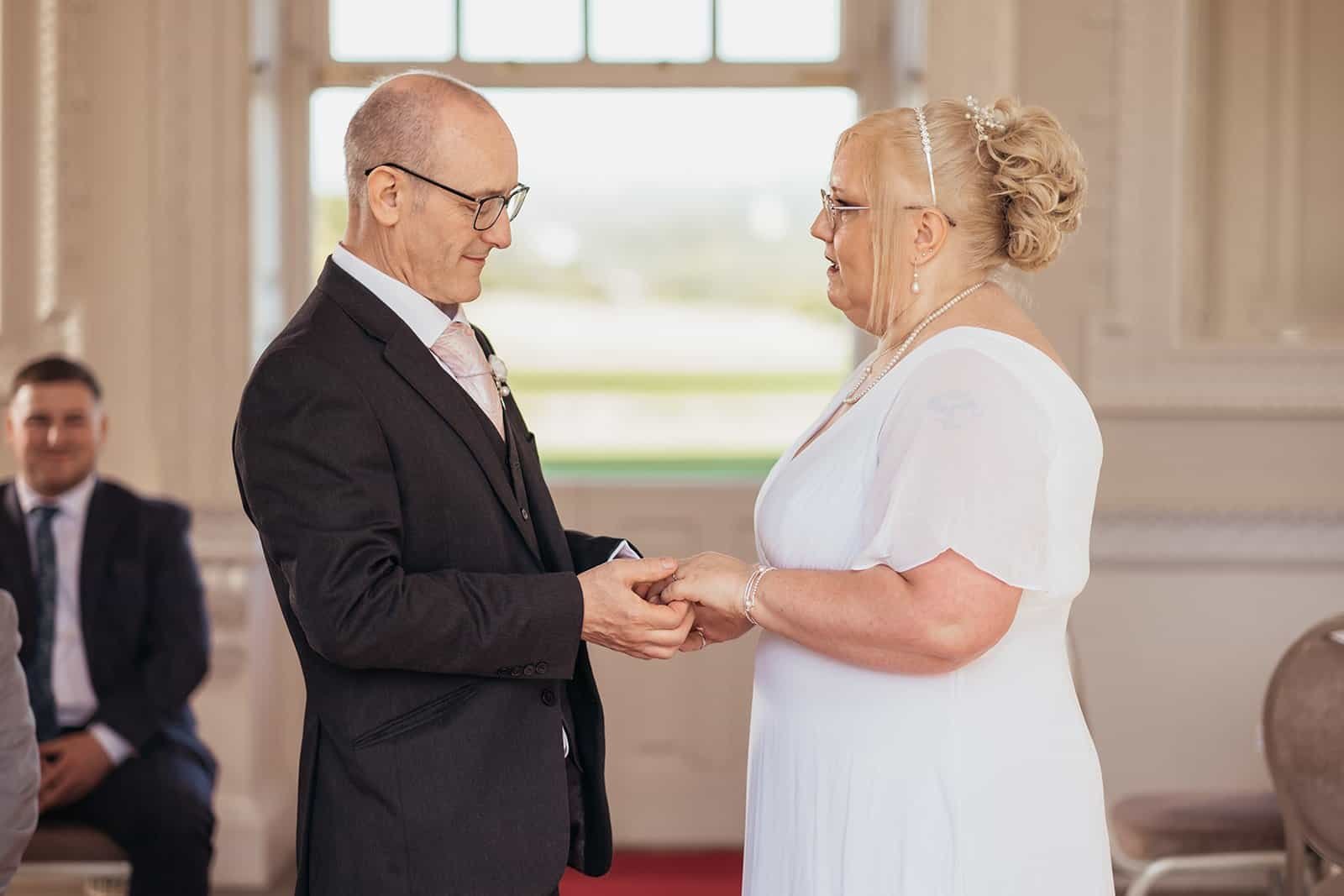 Senior couple exchanging vows at indoor wedding ceremony