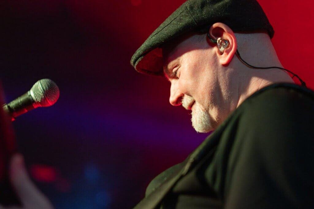 Musician in black hat performing live on stage with microphone